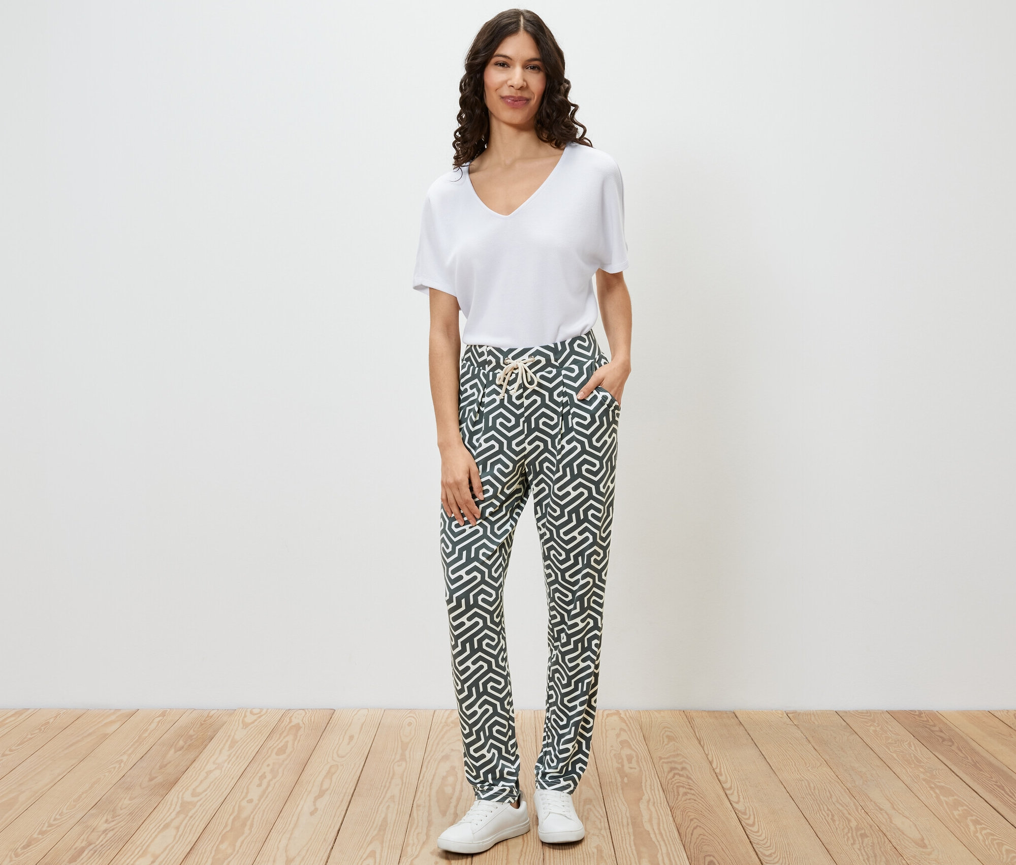 Femme posant, portant un pantalon en jersey imprimé vert.