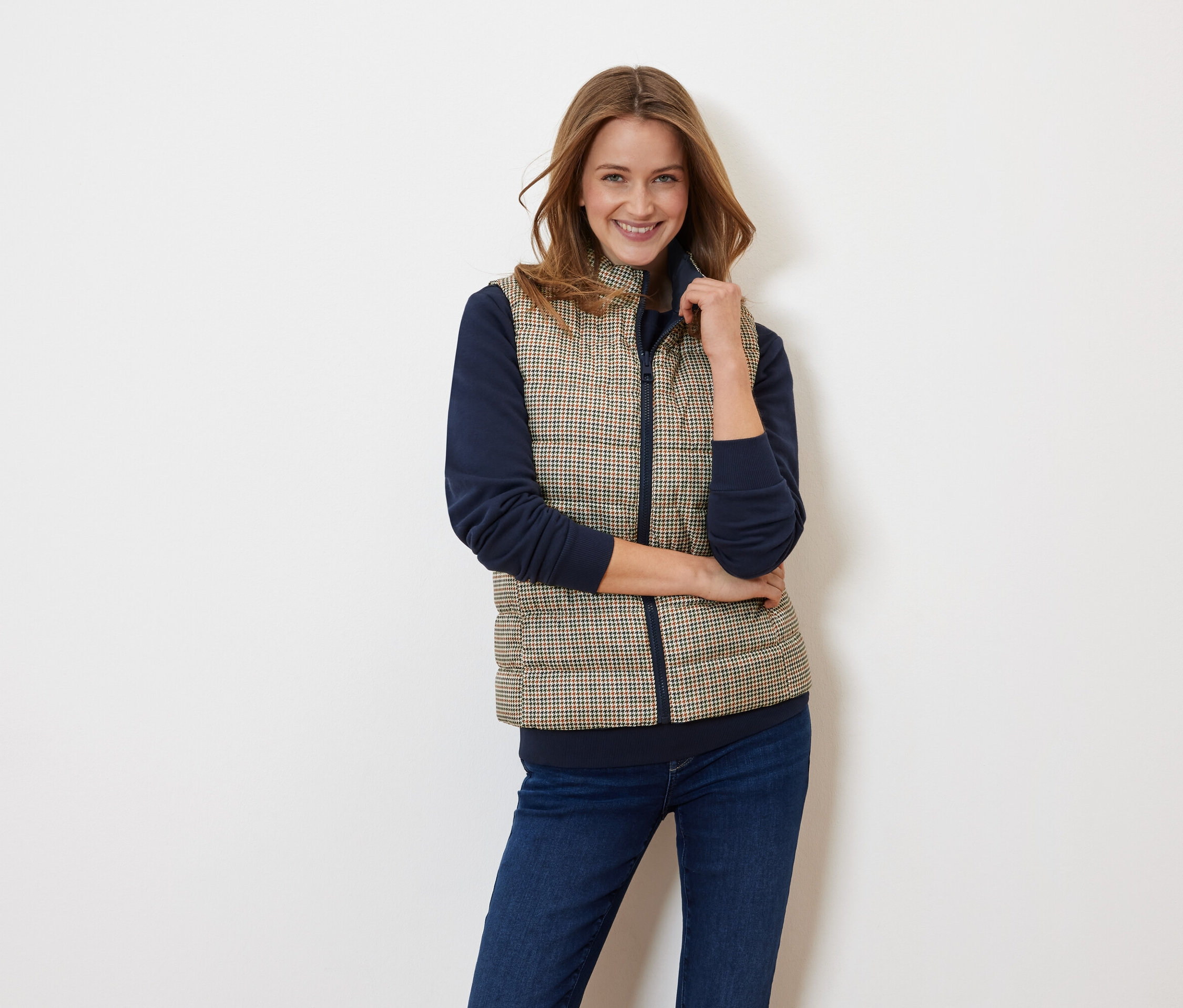 Femme posant portant un gilet matelassé et un haut bleu marine.