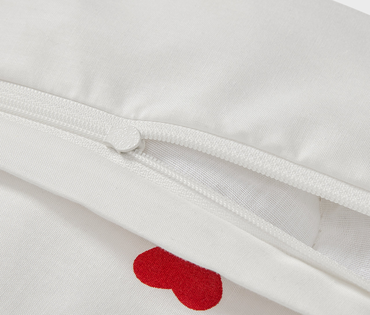 Détail d'une parure de lit en renforcé pour enfant, 100 x 135 cm, avec des cœurs rouges et une fermeture éclair.