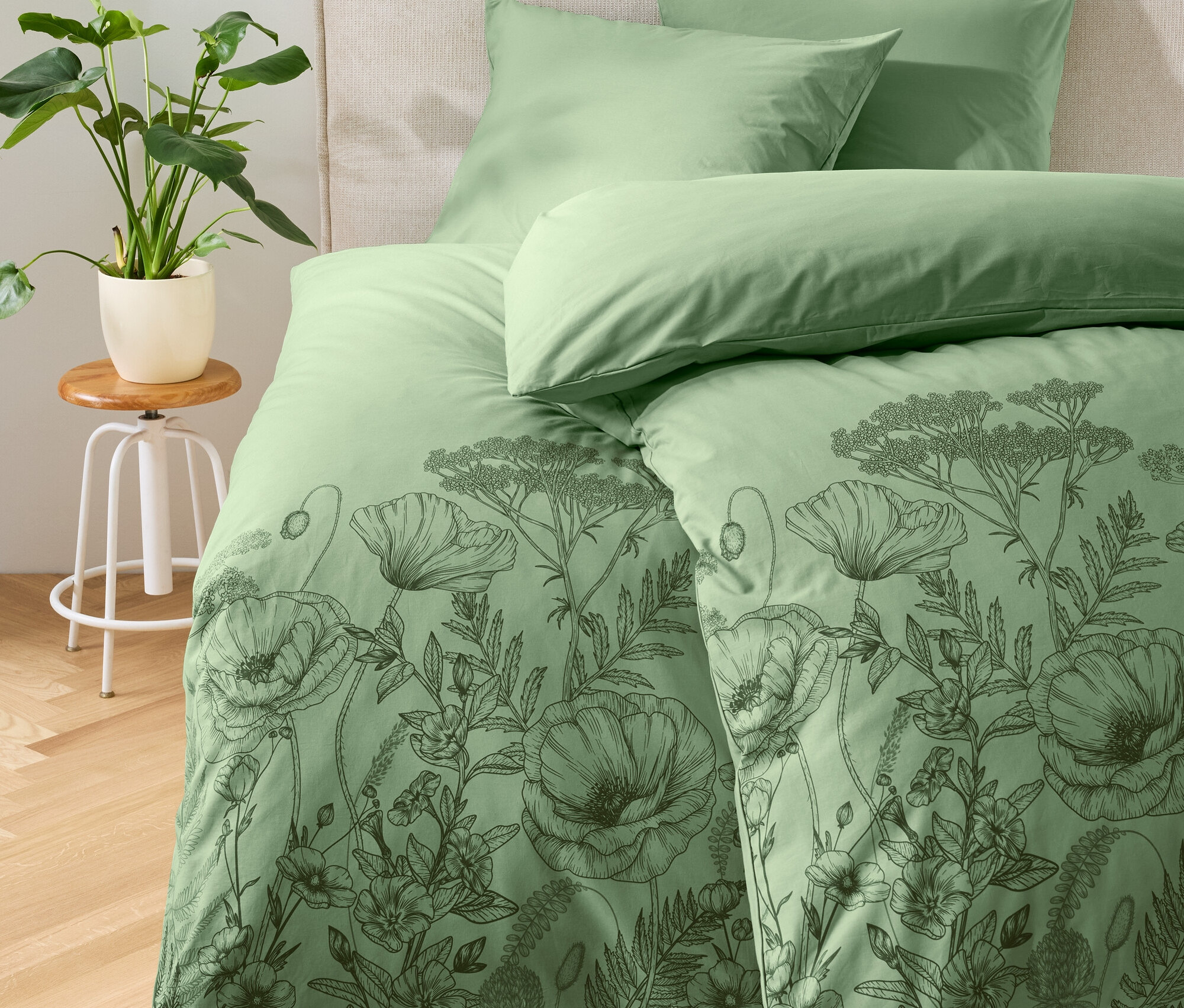 Linge de lit vert à motif floral sur un lit.