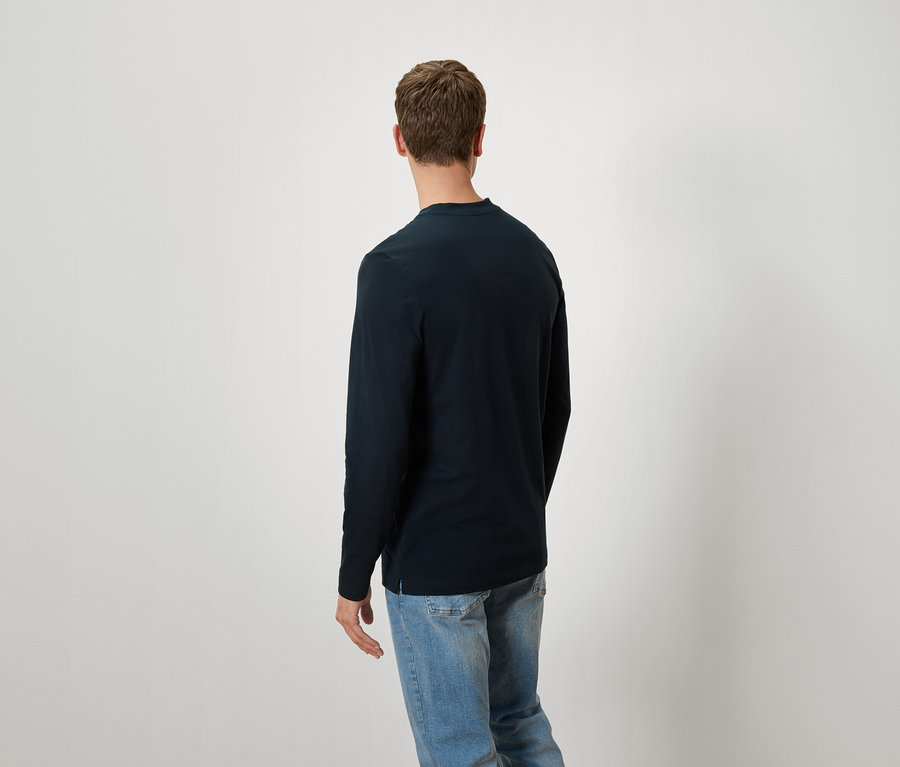 Homme de dos portant un t-shirt à manches longues bleu marine et un jean bleu.