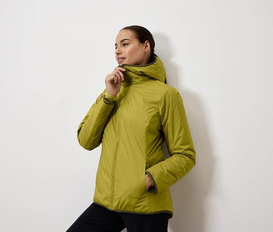 Femme fermant une veste à capuche jaune-vert.