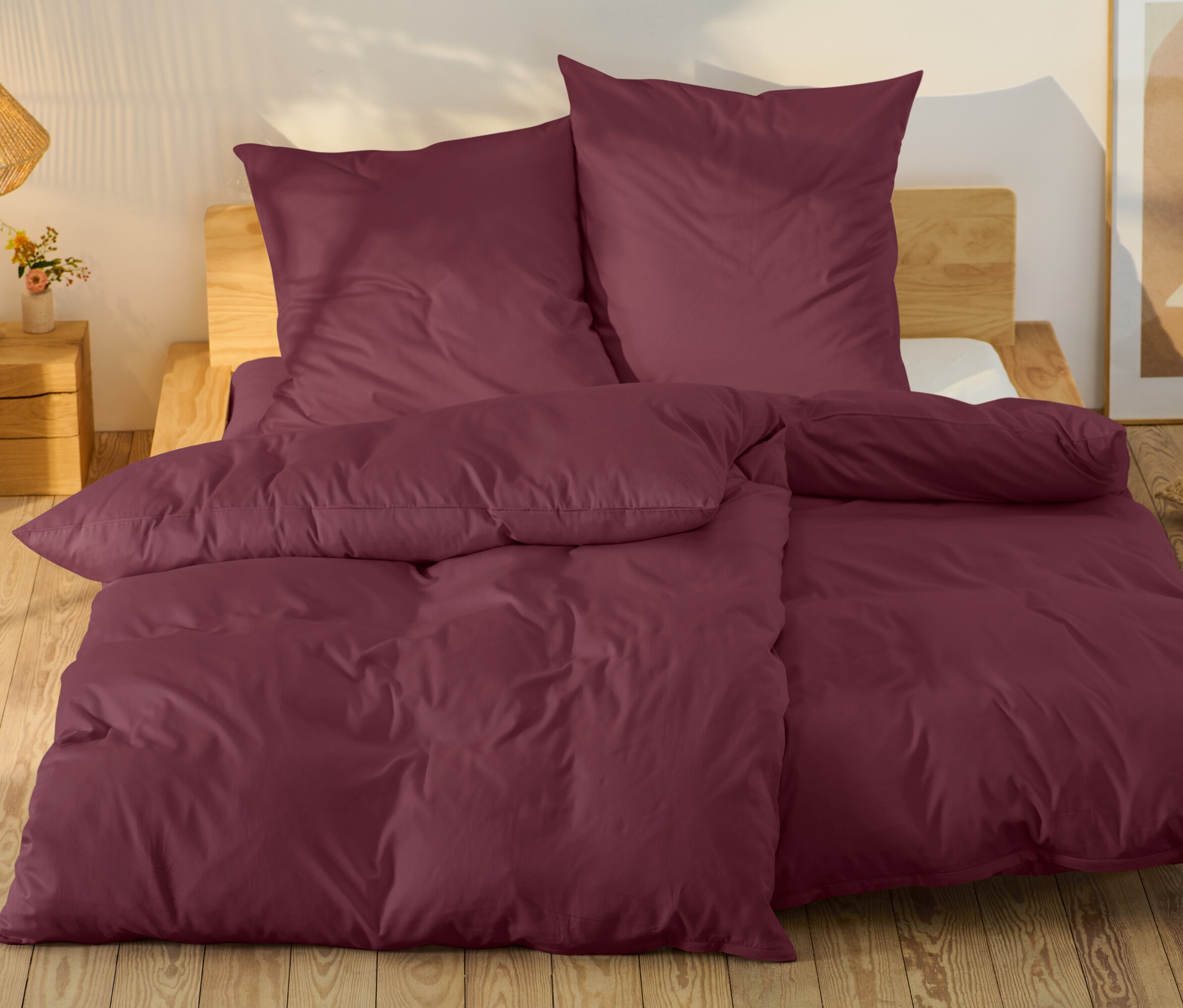 Linge de lit bordeaux sur un lit avec un cadre en bois.