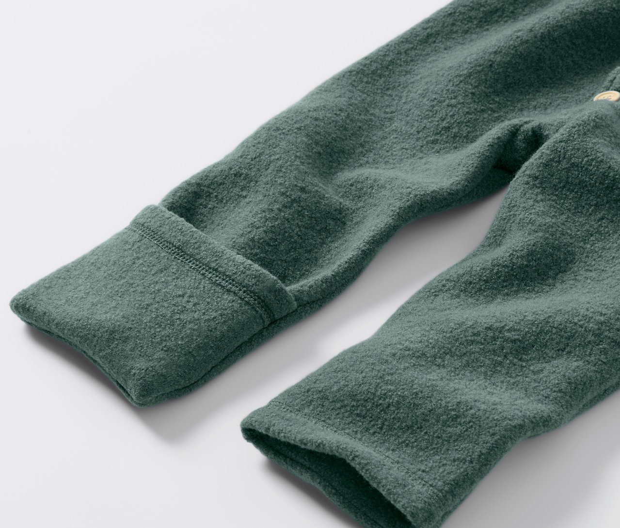 Gros plan sur une combinaison en laine mérinos verte pour bébé.