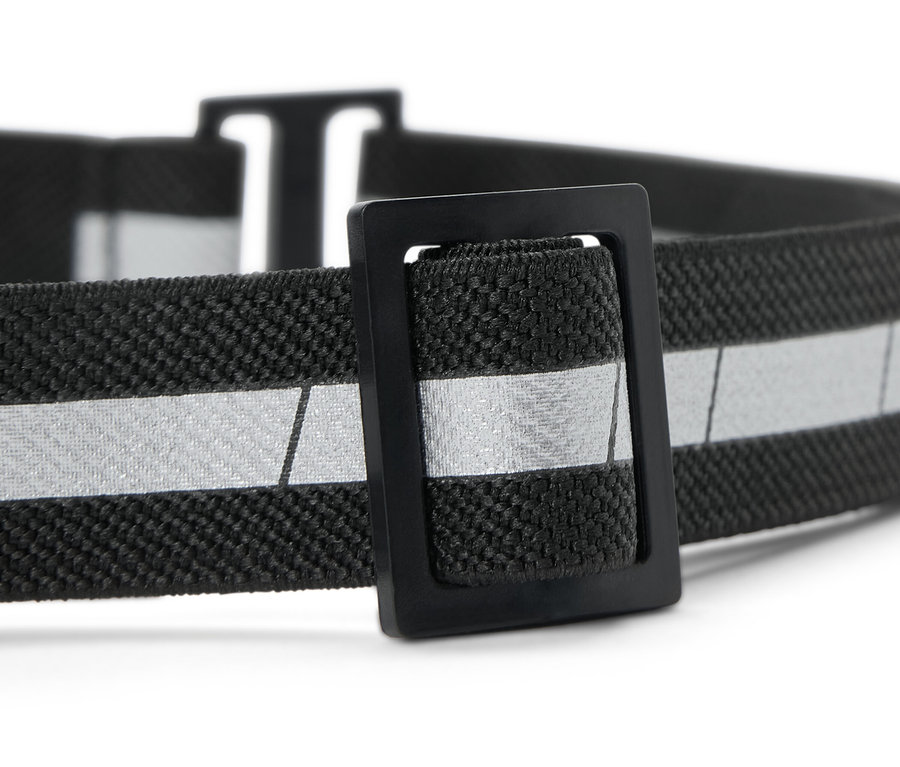 Gros plan d'une lampe frontale compacte avec un élastique noir et une bande réfléchissante argentée.