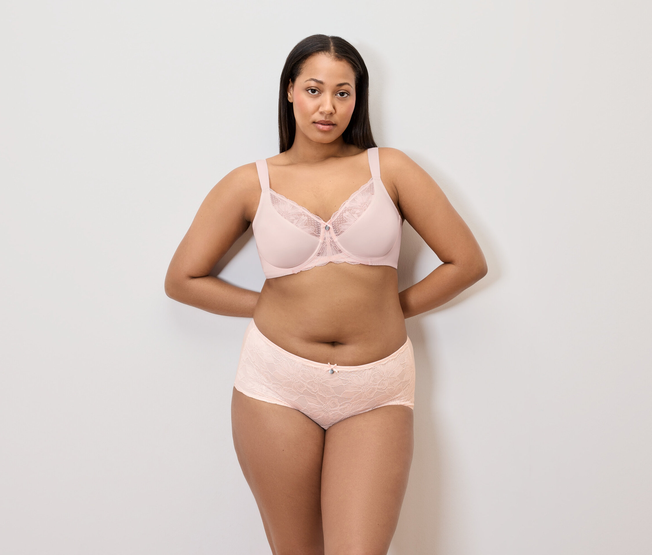 Femme posant en soutien-gorge et culotte rose clair.