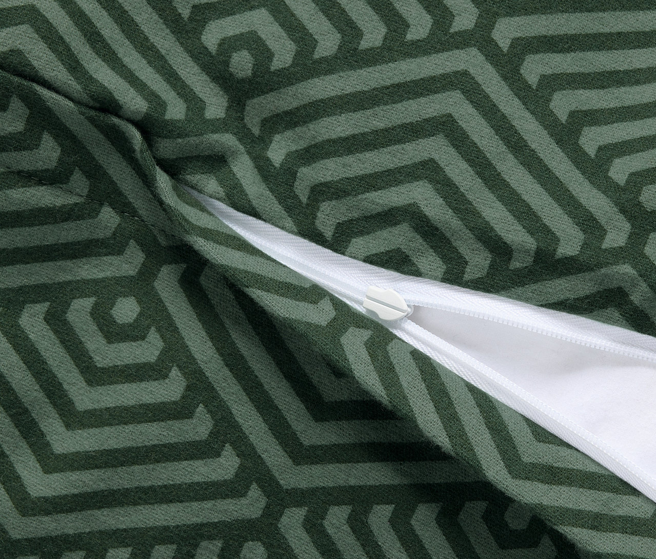 Gros plan sur deux taies d'oreiller en molleton vertes avec un motif géométrique et une fermeture éclair.