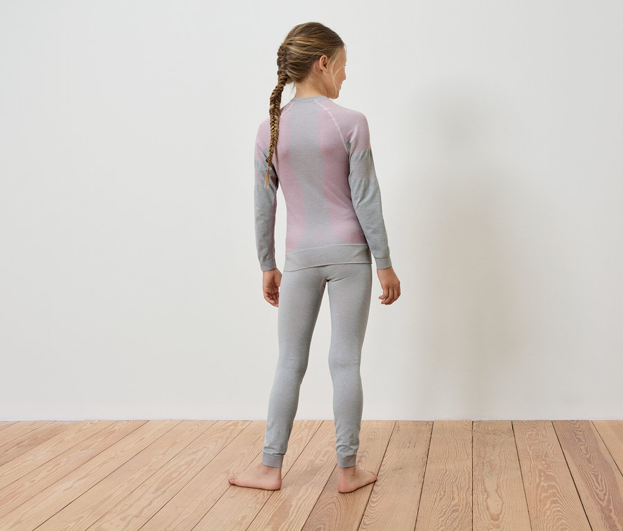 Une fille avec une tresse se tient dos à la caméra et porte des sous-vêtements thermiques gris.