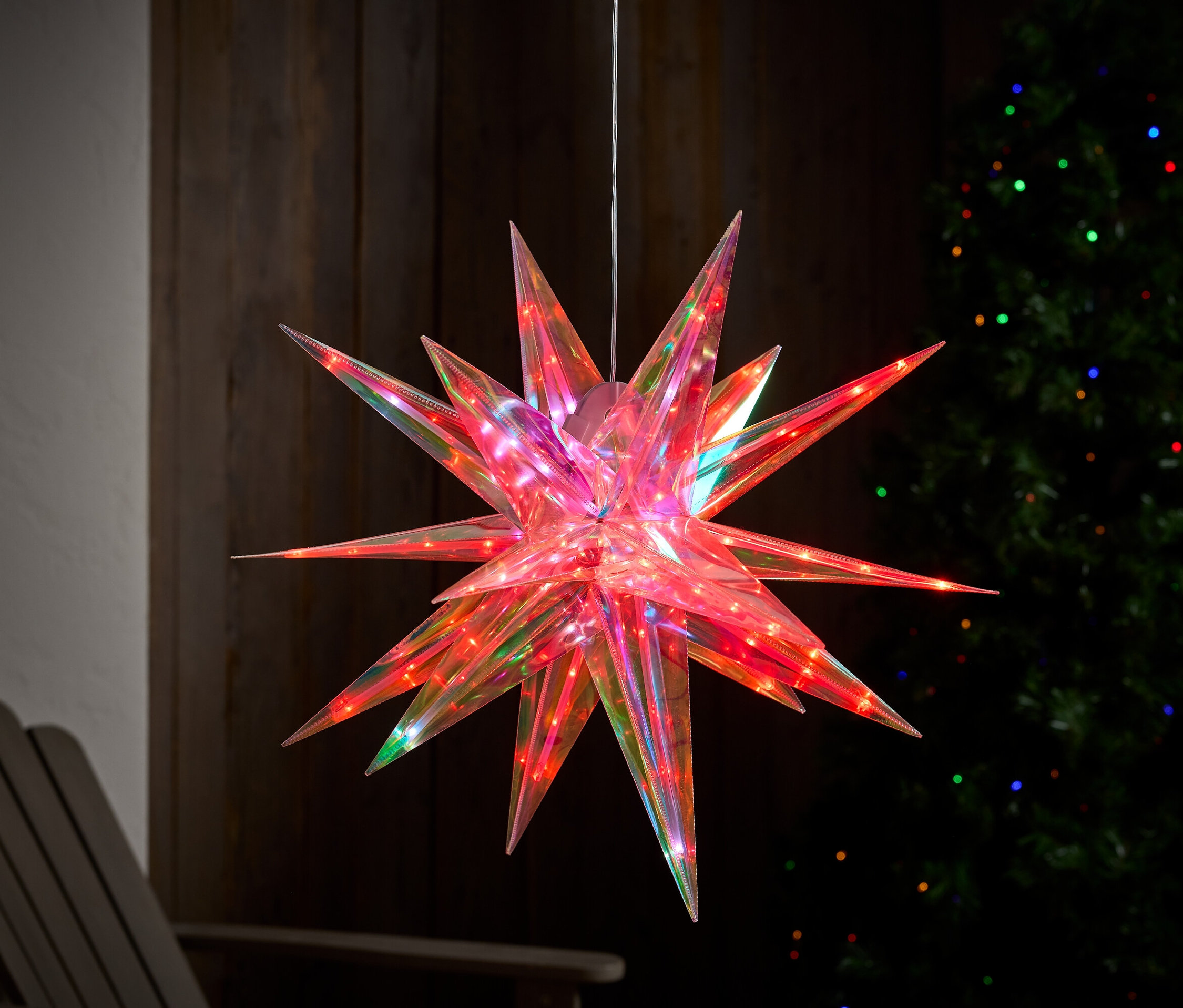 Une étoile rouge suspendue avec des lumières multicolores en arrière-plan.