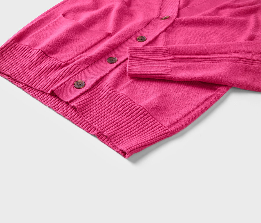 Gros plan sur un cardigan rose avec des boutons et une poche.