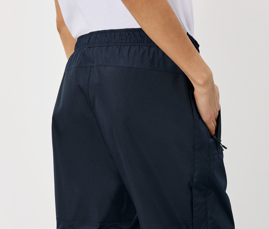 Personne avec une main dans la poche d'un pantalon bleu marine avec une taille élastique.