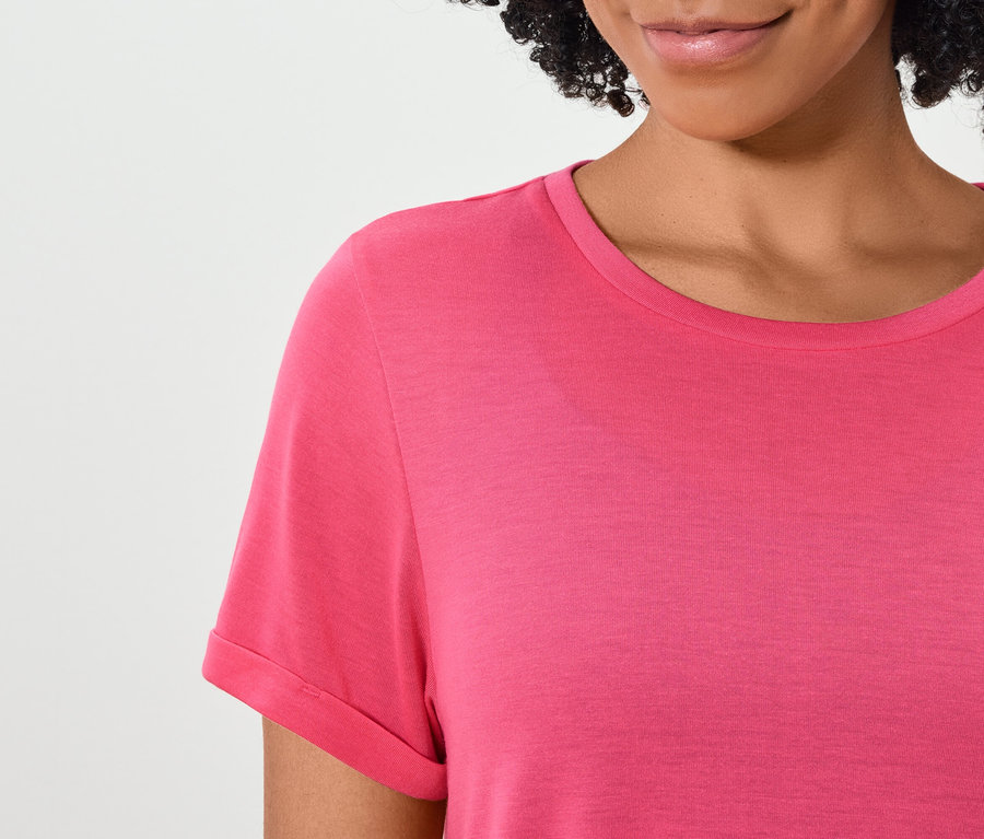 Haut du corps d'une femme aux cheveux foncés portant un t-shirt rose à manches courtes.