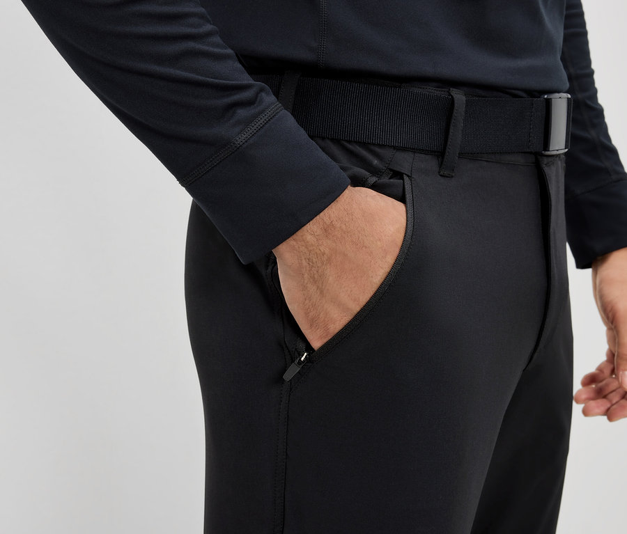 Un homme a la main dans la poche d'un pantalon noir avec une ceinture.