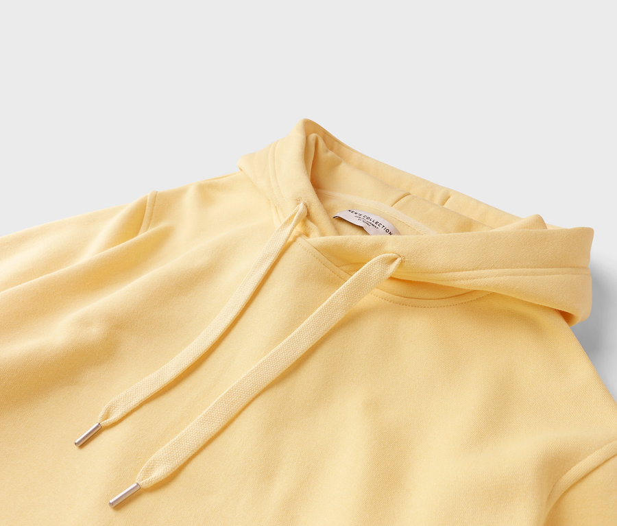 Gros plan d'un sweat à capuche jaune clair avec cordon de serrage.