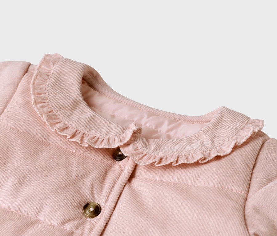 Gros plan d'une veste en velours côtelé rose avec un col à volants et des boutons marron.