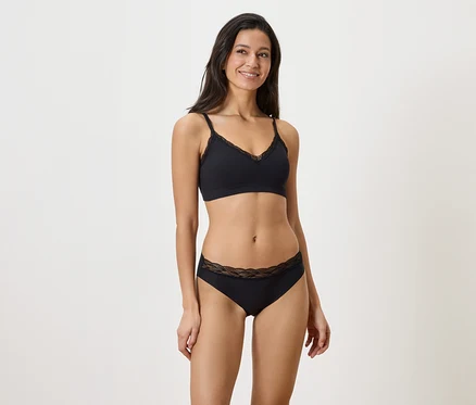 Femme portant un soutien-gorge noir avec des détails en dentelle et une culotte noire avec des détails en dentelle.