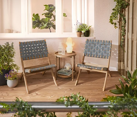 Deux chaises tressées et une table d'appoint sont installées sur une terrasse.