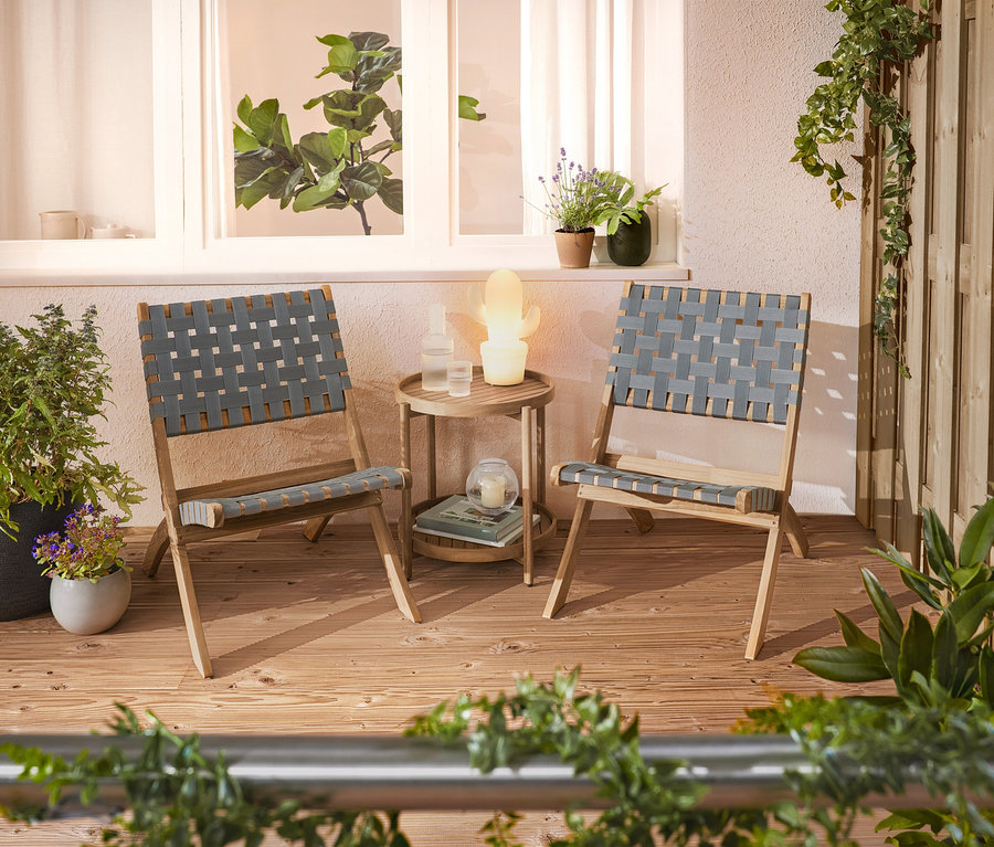 Deux chaises tressées et une table d'appoint sont installées sur une terrasse.