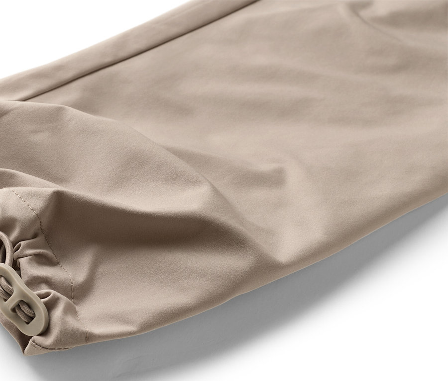 Gros plan sur le bas d'un pantalon beige avec élastique et cordon de serrage.