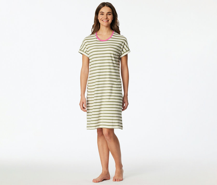 Une femme souriante est debout pieds nus, vêtue d'une chemise de nuit SCHIESSER à rayures horizontales vert olive et blanc cassé avec un liseré rose au col.