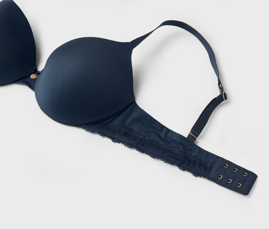 Gros plan d'un soutien-gorge bleu marine avec de la dentelle sur fond blanc.