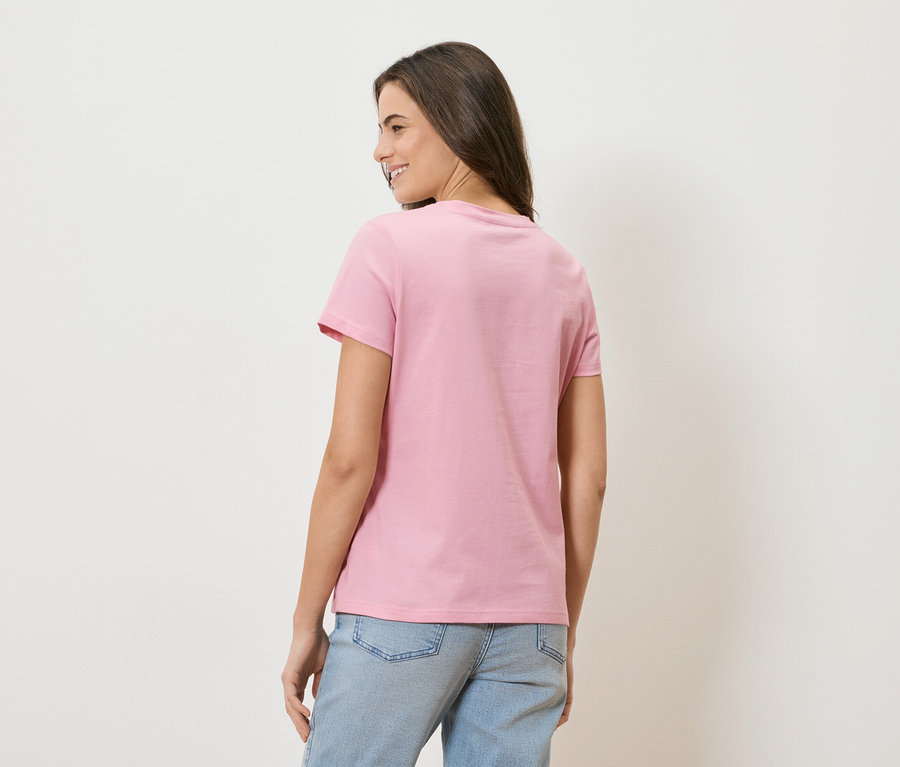 Femme vue de dos, portant un t-shirt rose et un jean bleu clair.