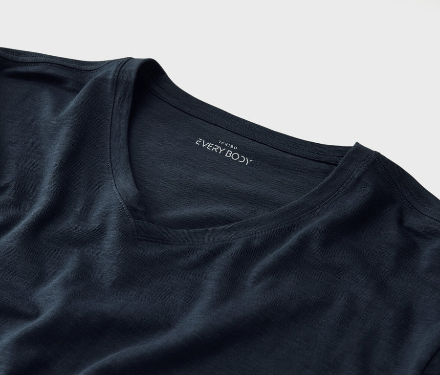 Gros plan d'un T-shirt bleu marine à col en V avec l'inscription "Tchibo EVERY BODY" sous le col.