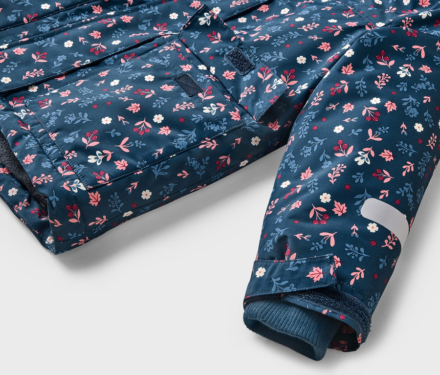 Gros plan sur une veste bleu marine à motifs floraux, une poche et une manche avec une bande réfléchissante.