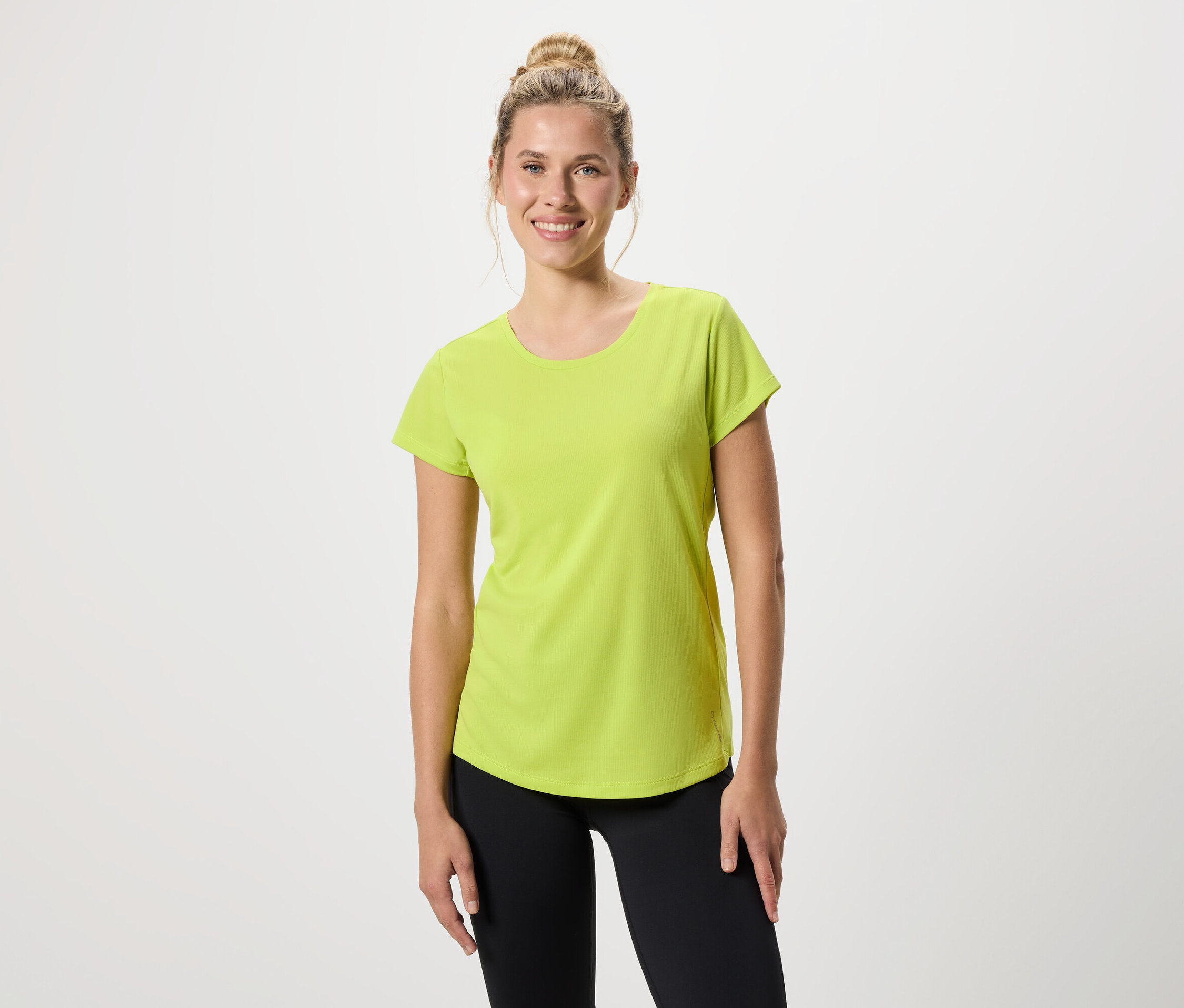 Une femme porte un t-shirt vert clair et un legging noir.