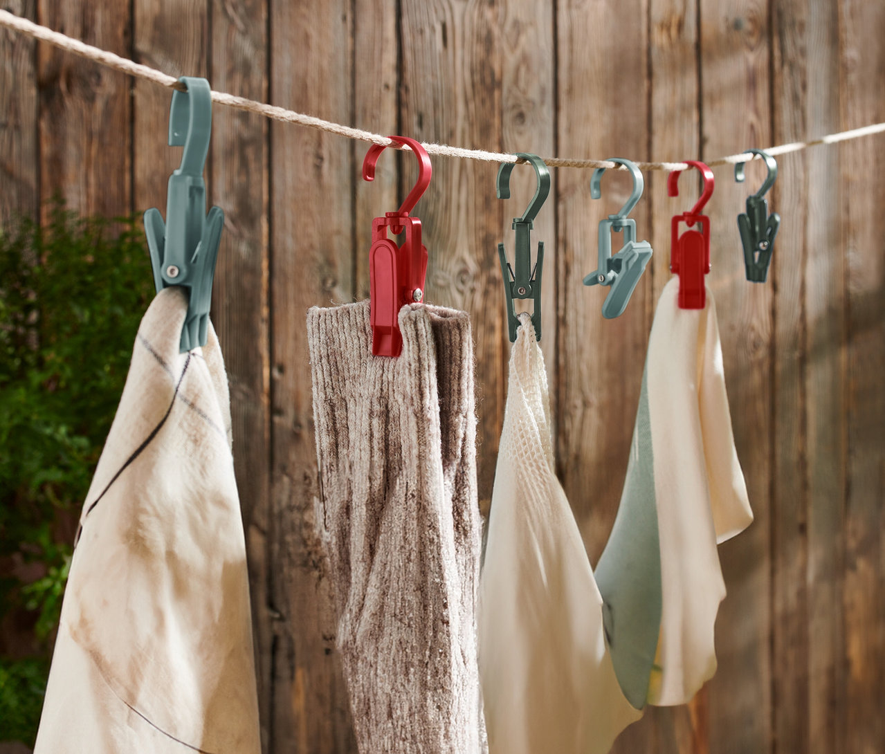 Des pinces à linge multicolores sont suspendues à une corde à linge devant un mur en bois.