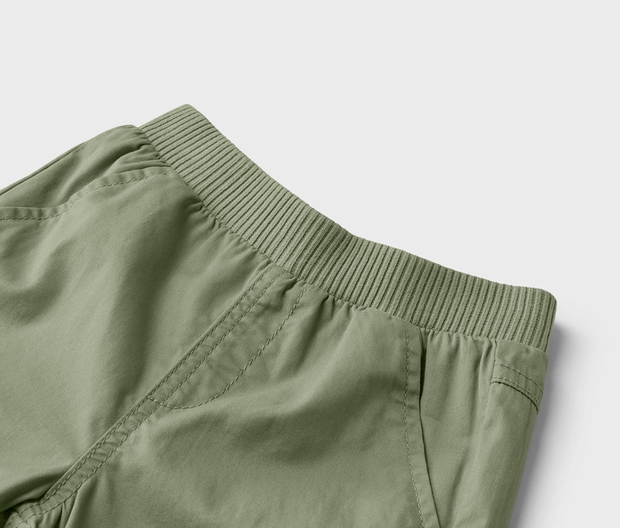 Gros plan sur un pantalon vert olive avec une taille élastique et des poches.