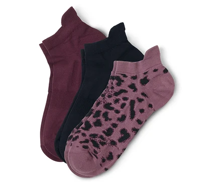 Trois chaussettes courtes sont superposées : une bordeaux, une noire et une mauve à taches noires.