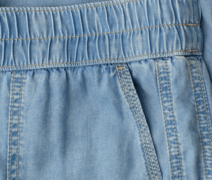 Gros plan sur un pantalon bleu clair avec une taille élastique et une poche plaquée.