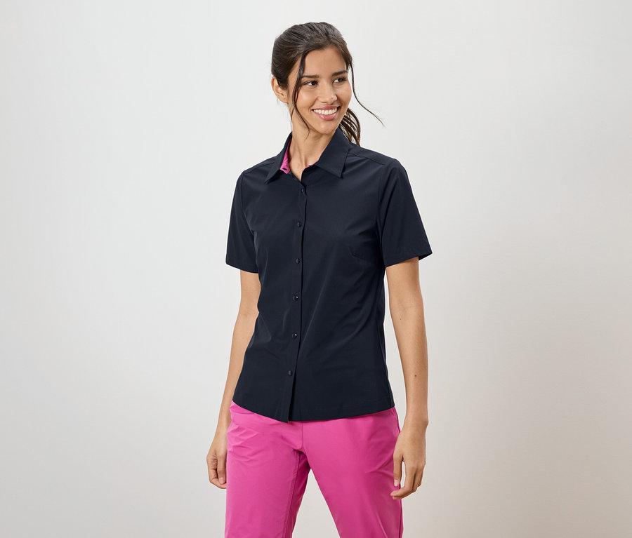 Femme portant une chemise bleu marine à manches courtes et un pantalon rose.