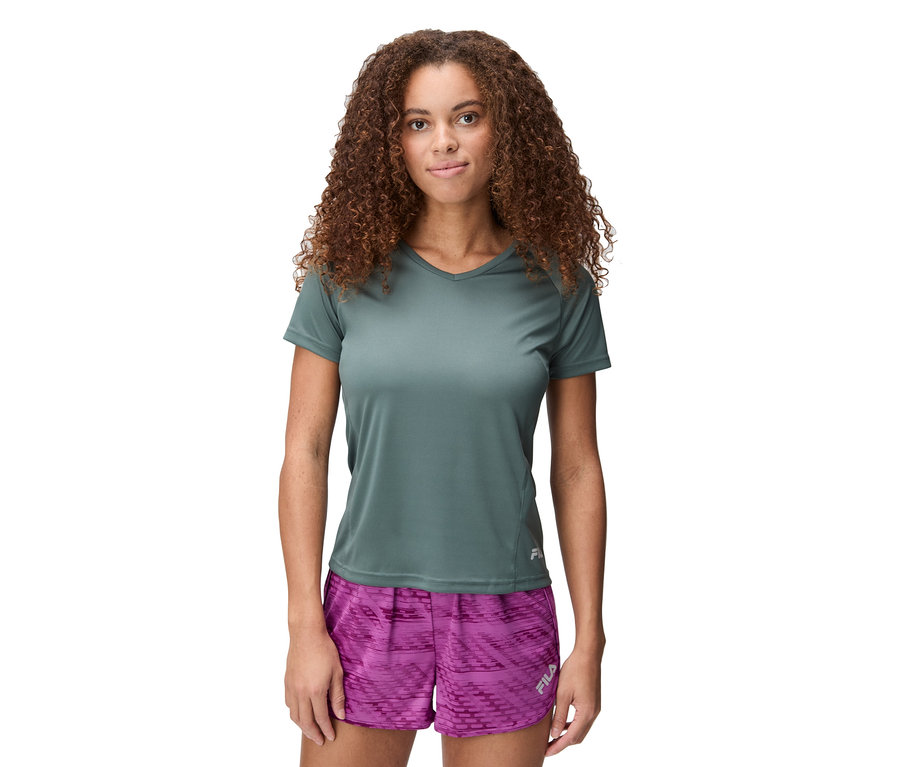 Femme aux cheveux bouclés portant un t-shirt gris et un short rose.