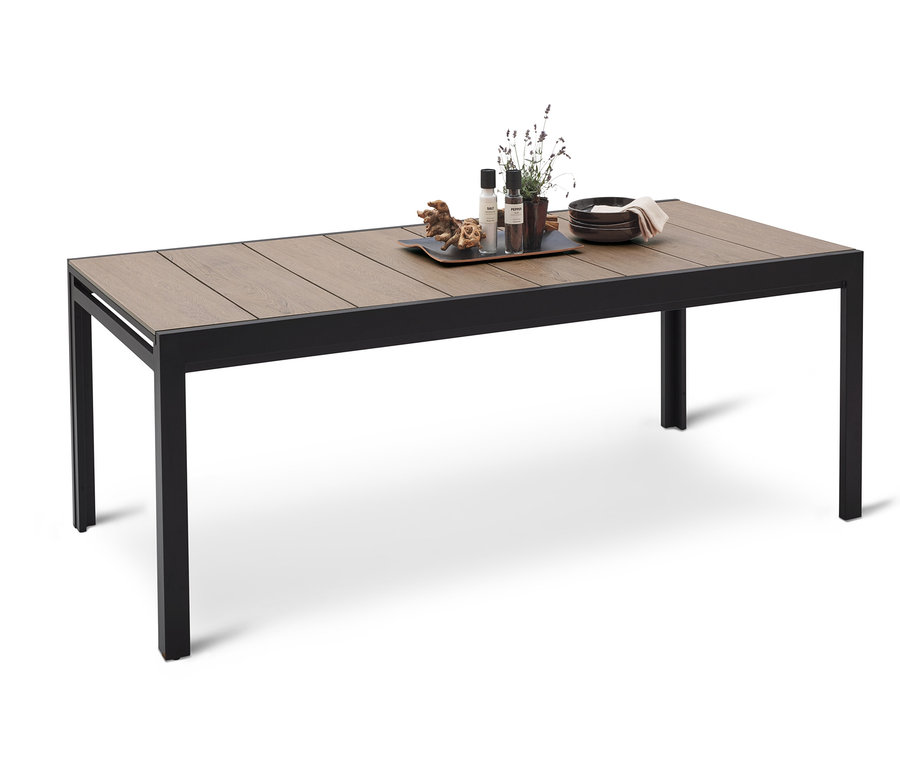 Table à manger avec plateau en bois et cadre en métal noir. Des assiettes, des objets décoratifs et des plantes sont posés sur la table.