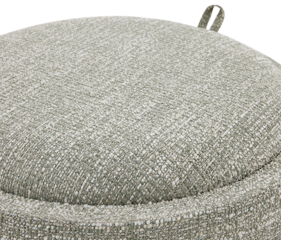 Gros plan d'un pouf ou coussin rond vert clair avec une texture de tissu tissé grossier et tacheté, et une petite boucle en tissu sur le dessus.