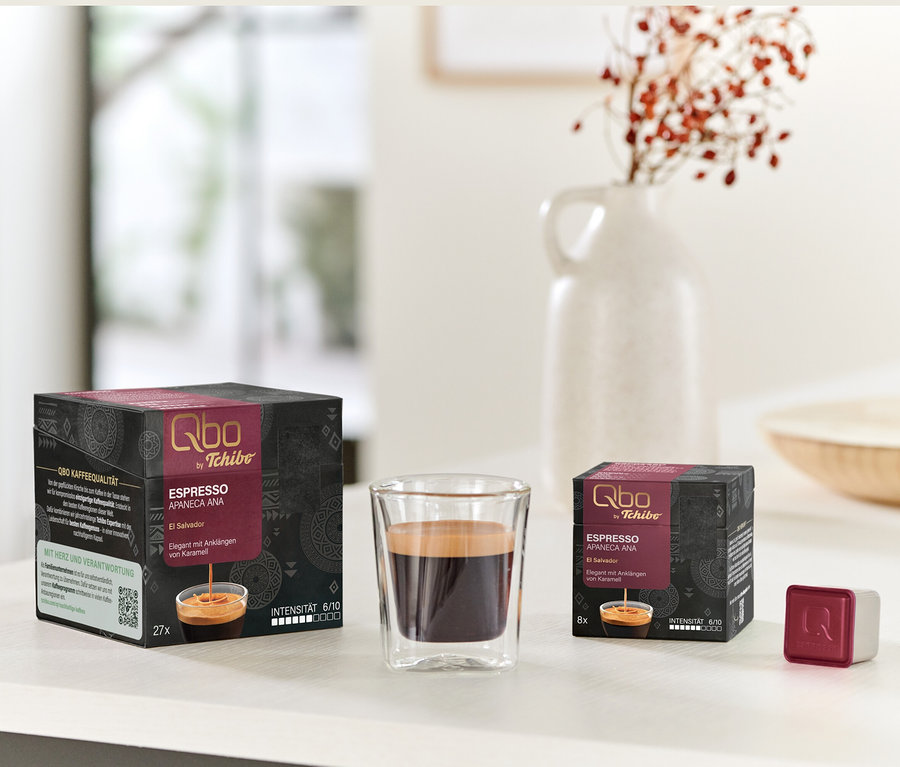 Packs de Qbo Espresso APANECA ANA de 27 et 8 capsules à côté d'un verre d'espresso et d'un seul cube de capsule.