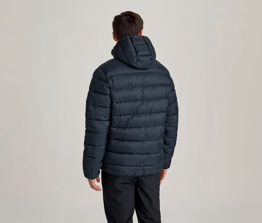 Personne vue de dos, portant une doudoune à capuche bleu foncé et un pantalon noir.