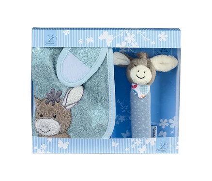 Un coffret cadeau pour bébé dans une boîte rayée bleu clair et blanc avec une fenêtre transparente. À l'intérieur se trouvent un bavoir bleu clair avec une broderie de tête d'âne marron et un hochet avec une tête d'âne souriante et un manche bleu à étoiles blanches.