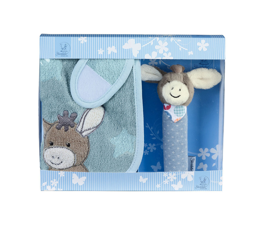 Un coffret cadeau pour bébé dans une boîte rayée bleu clair et blanc avec une fenêtre transparente. À l'intérieur se trouvent un bavoir bleu clair avec une broderie de tête d'âne marron et un hochet avec une tête d'âne souriante et un manche bleu à étoiles blanches.