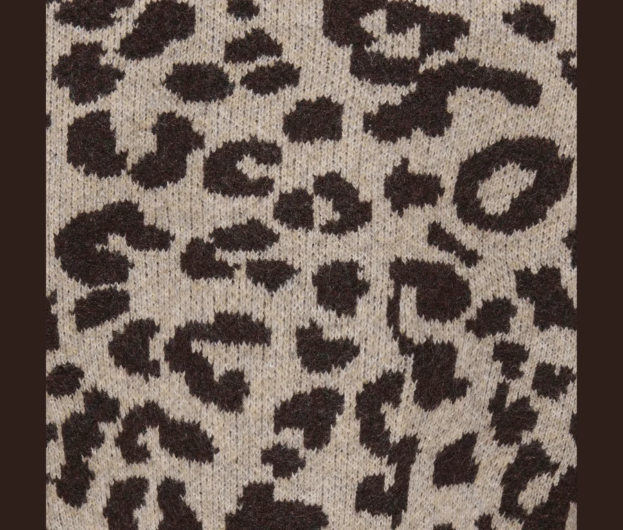 Gros plan d'un tissu tricoté avec un motif léopard beige et marron foncé.