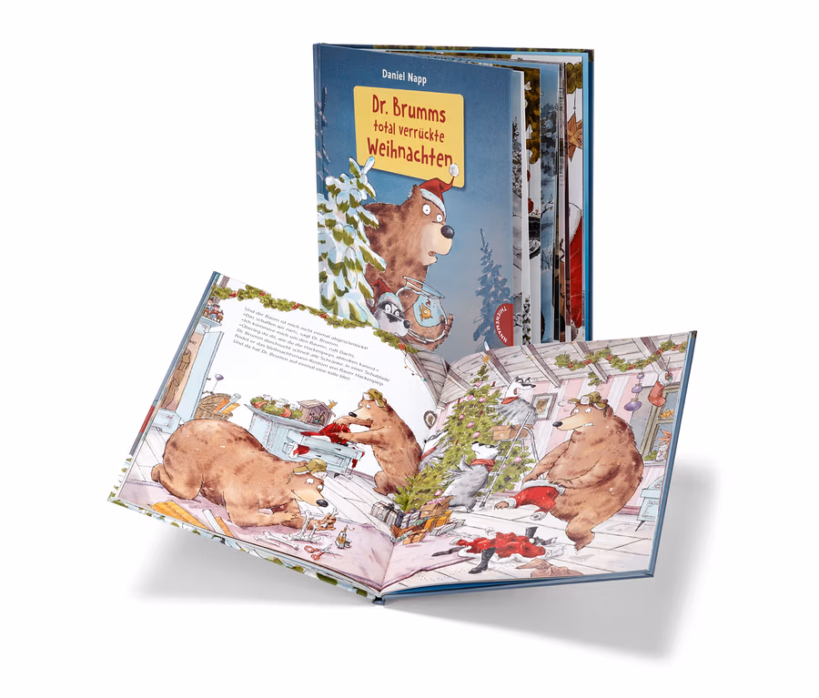 Livre ouvert « Dr. Brumms total verrückte Weihnachten » avec des illustrations d'ours et de ratons laveurs décorant un sapin de Noël, avec une autre édition du livre en arrière-plan.