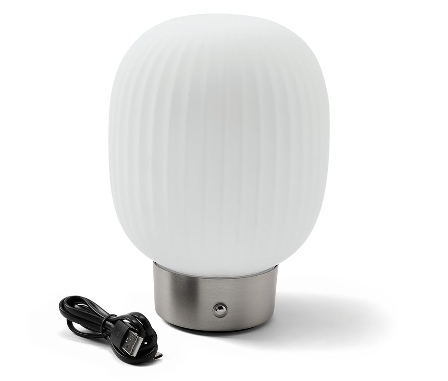 Une lampe de table à LED avec accumulateur et abat-jour en verre est posée à côté d'un câble de chargement noir.