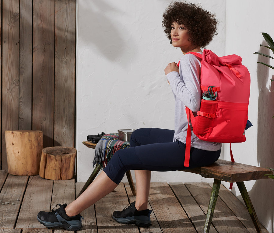 Femme assise avec un sac à dos outdoor rouge.