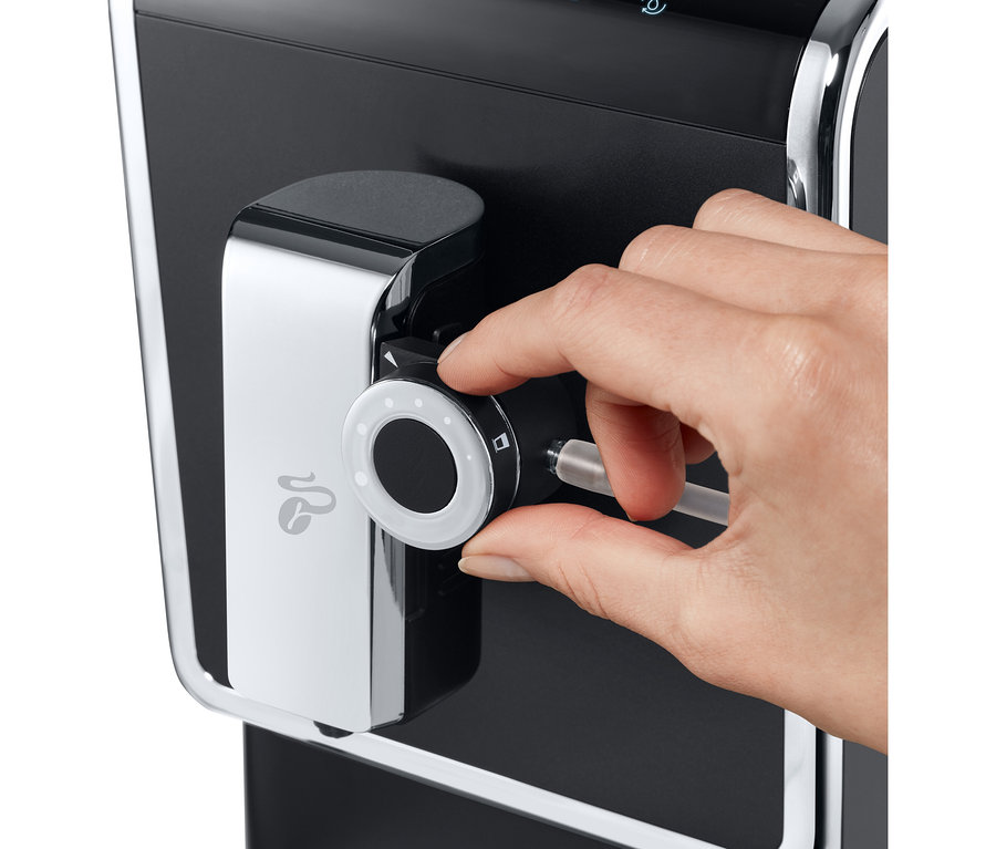 Une main ajuste la machine à café entièrement automatique de Tchibo « Esperto Pro » anthracite.