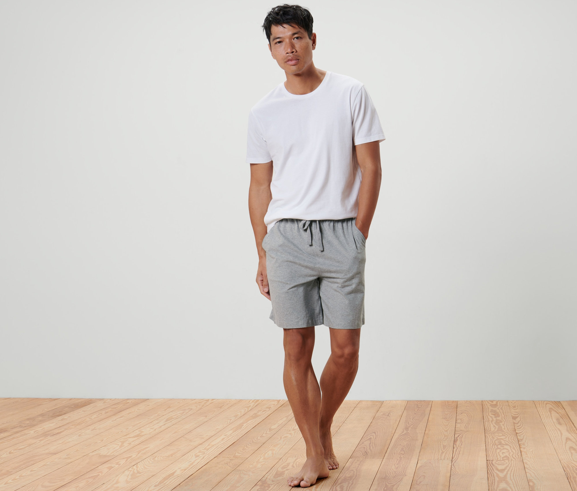 Un homme debout, les mains dans les poches d'un Short relax.