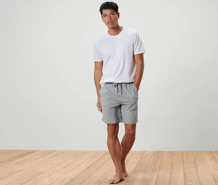 Un homme debout, les mains dans les poches d'un Short relax.
