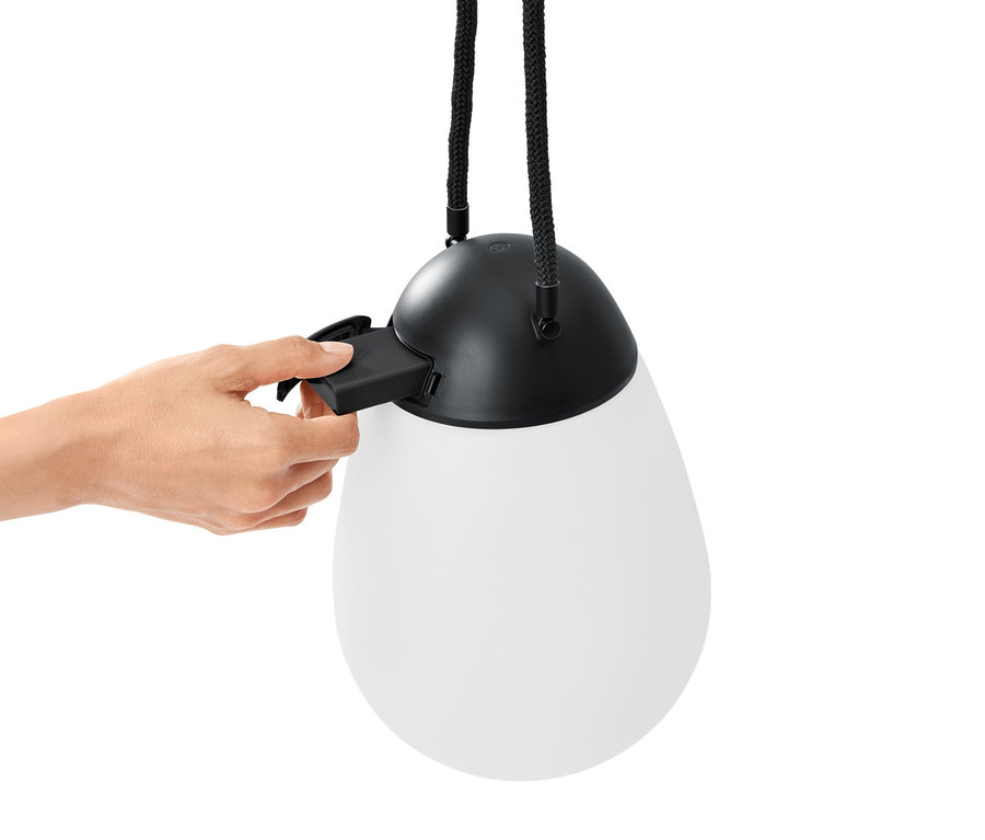 Une main insère une pile dans une lampe à LED rechargeable avec batterie interchangeable supplémentaire.