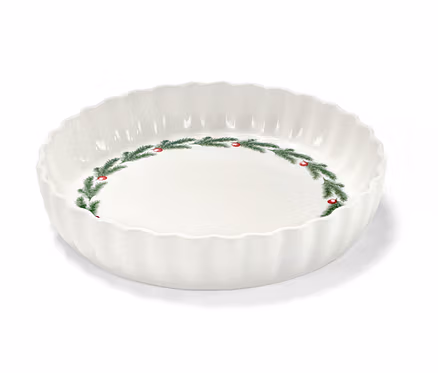Un moule à tarte blanc avec un motif de Noël de branches de sapin et de baies rouges.